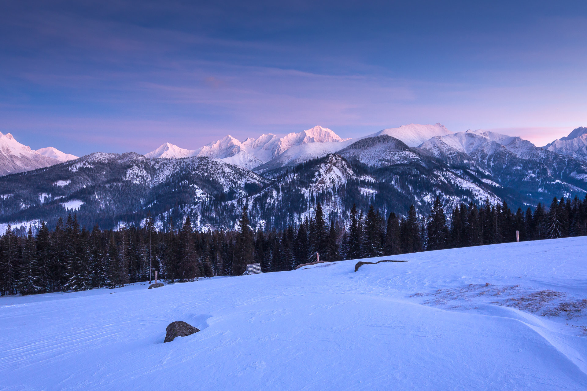 Canon 5D Mark III + Tokina AT-X PRO FX SD 16-28 mm f/2.8 | 28 mm, f/9, 13 s, ISO 500. Widok z Rusinowej Polany na Tatry Wysokie. Kompozycja opiera się na zasadzie trójpodziału z kamieniem w dolnym lewym mocnym punkcie. Dodatkowo wykorzystałem linie na śniegu z prawej strony by wprowadzała wzrok widza do środka kadru.